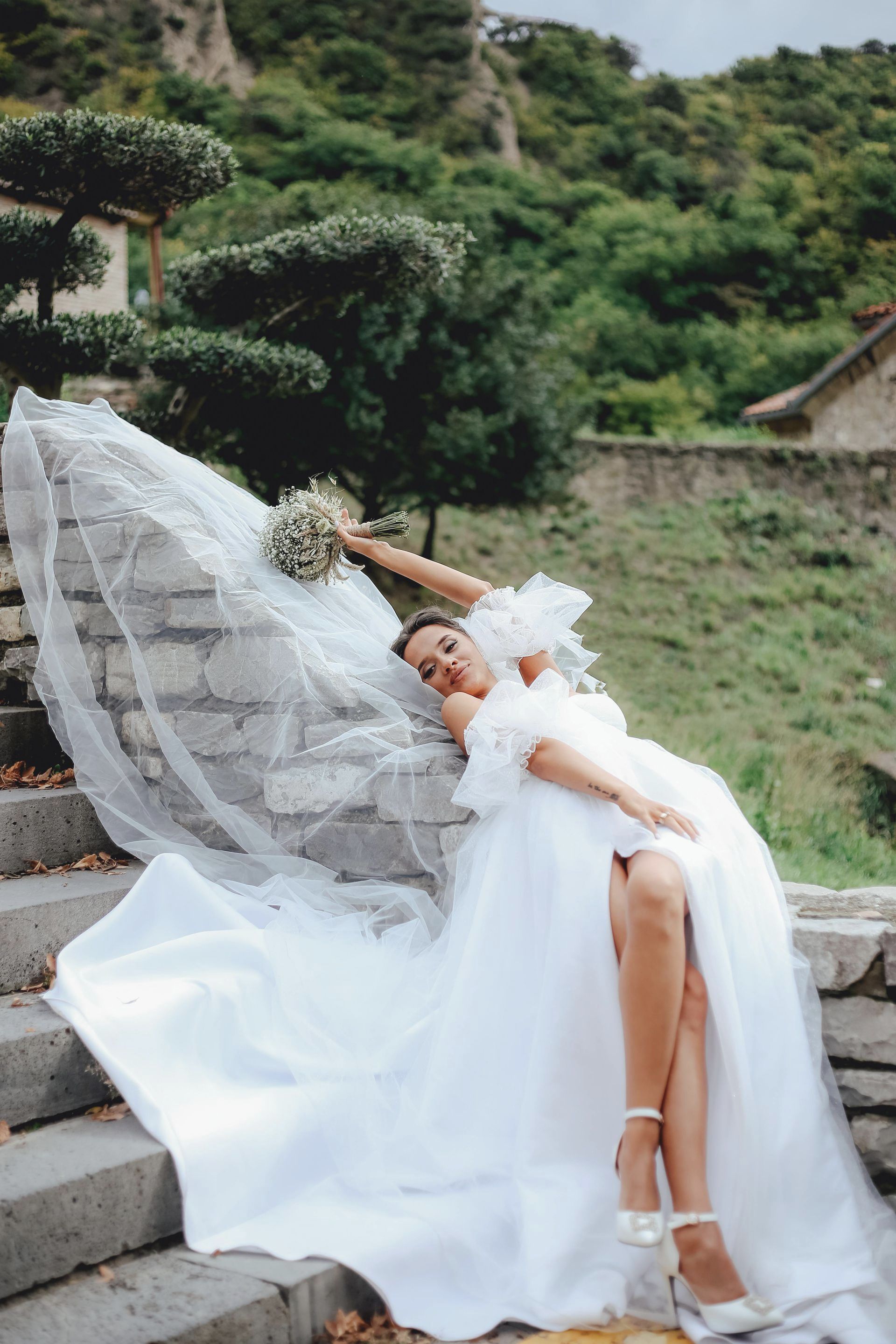 A woman in a wedding dress is laying on a set of stairs.