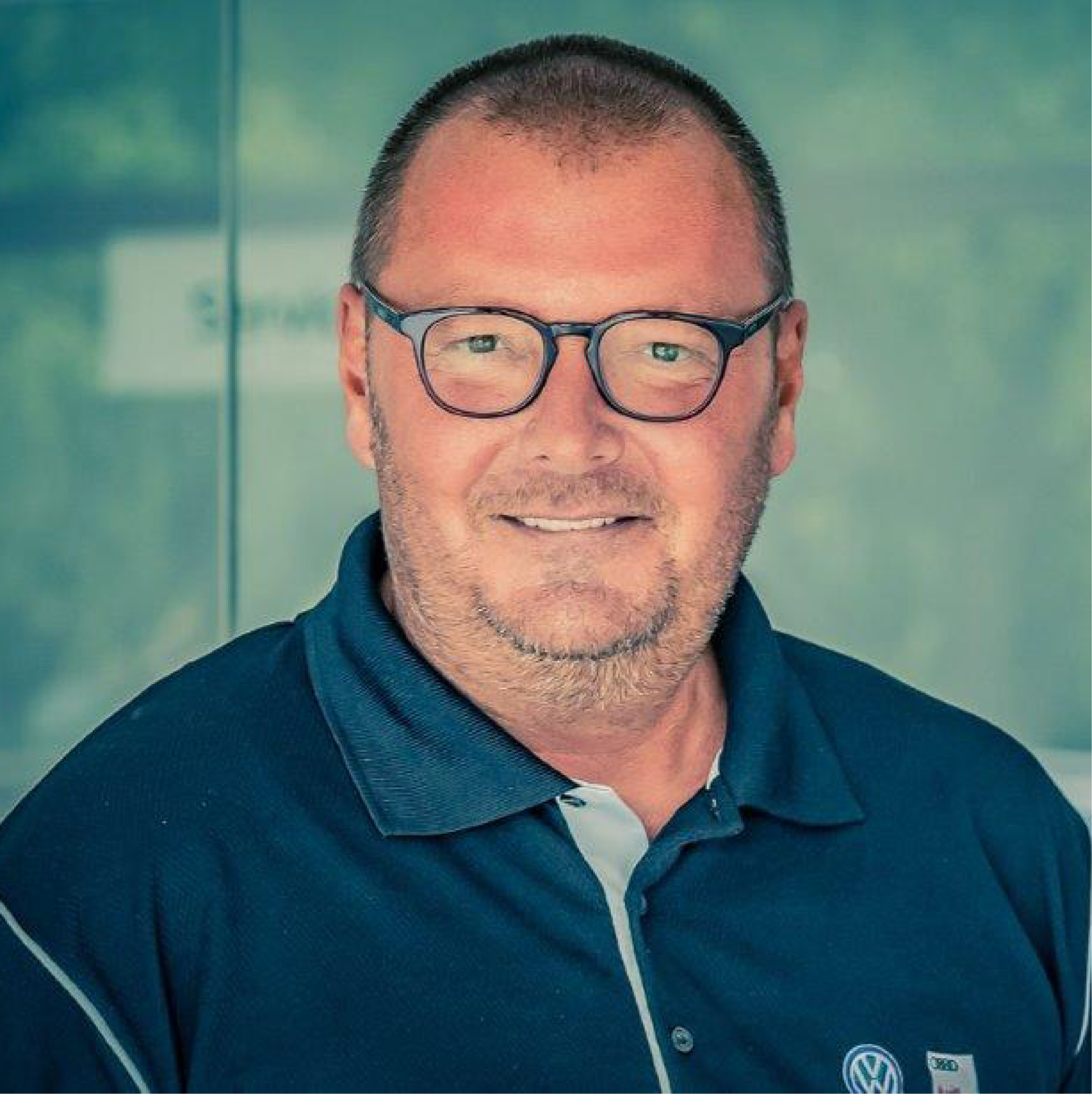 Ein Mann mit Brille und blauem Hemd lächelt in die Kamera