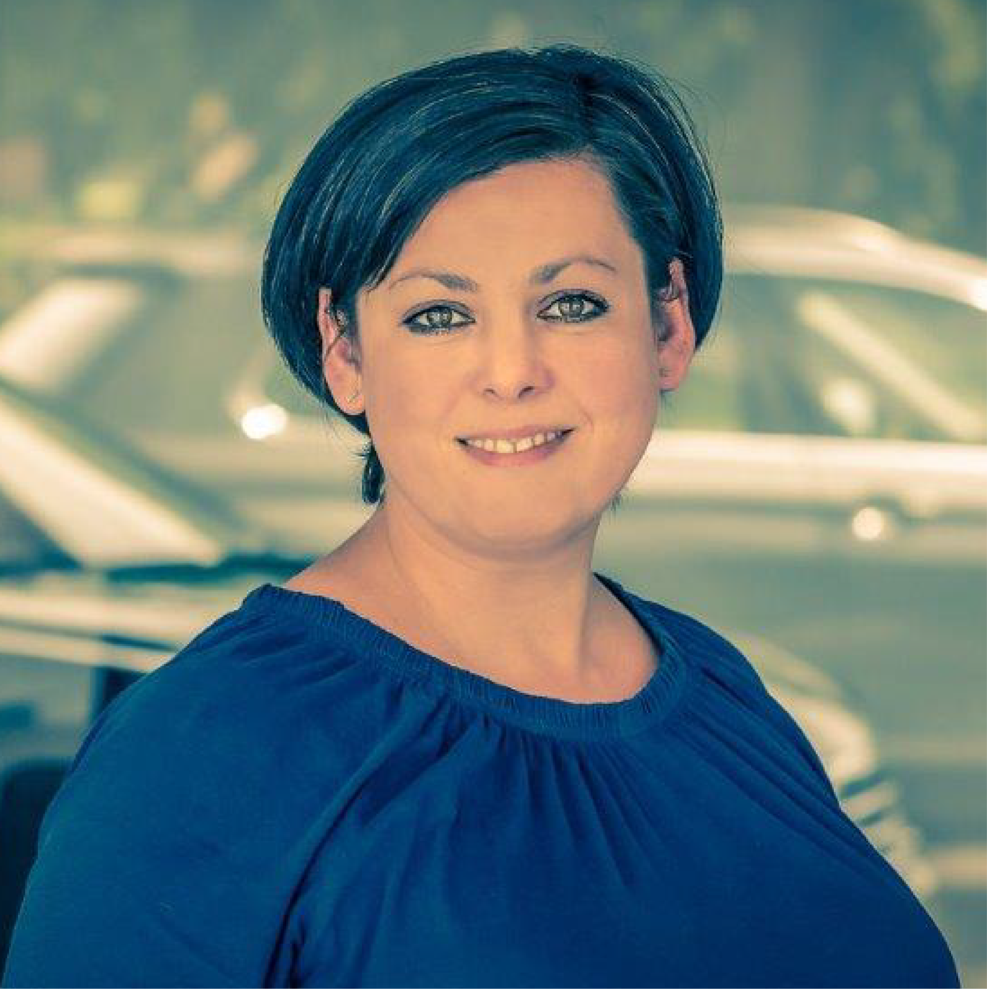 Eine Frau in einem blauen Hemd lächelt in die Kamera