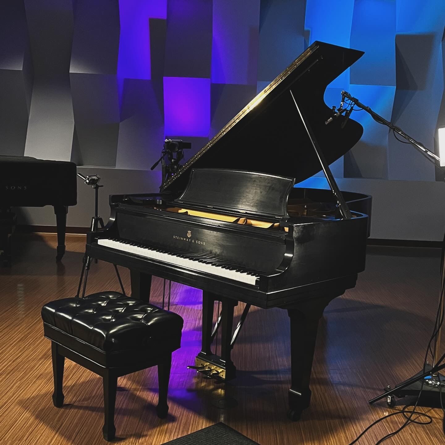A piano is sitting in a room with purple and blue lights