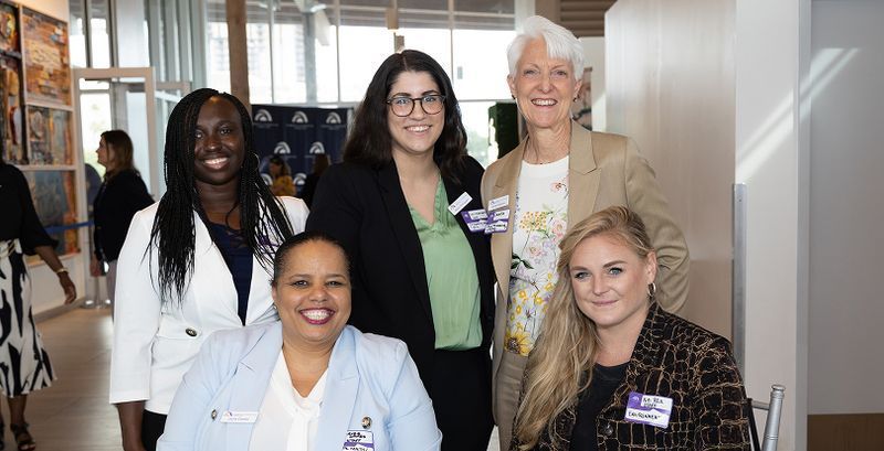 A group of women are posing for a picture together in a room.