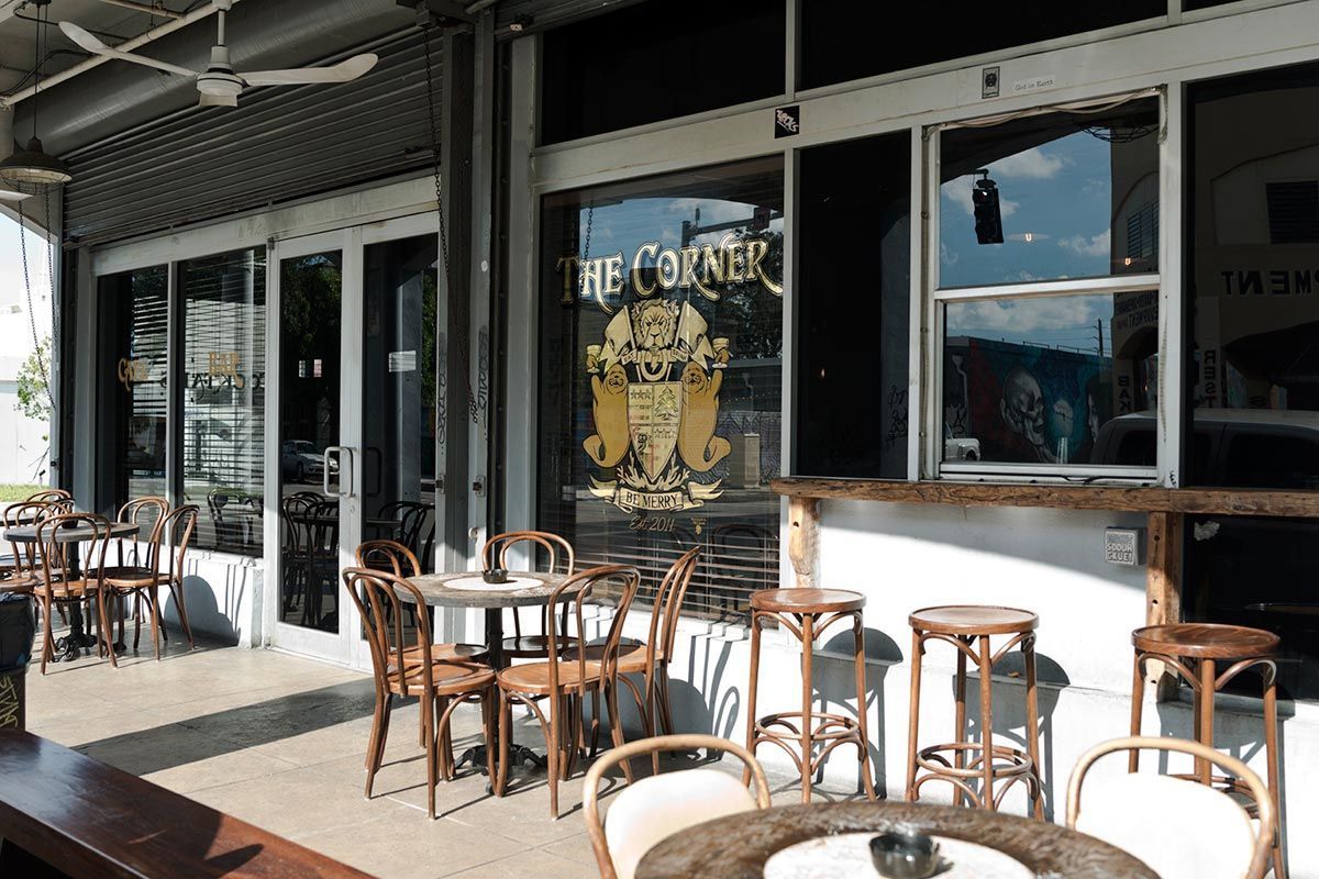 Outdoor cafe with tables and chairs, storefront with logo.