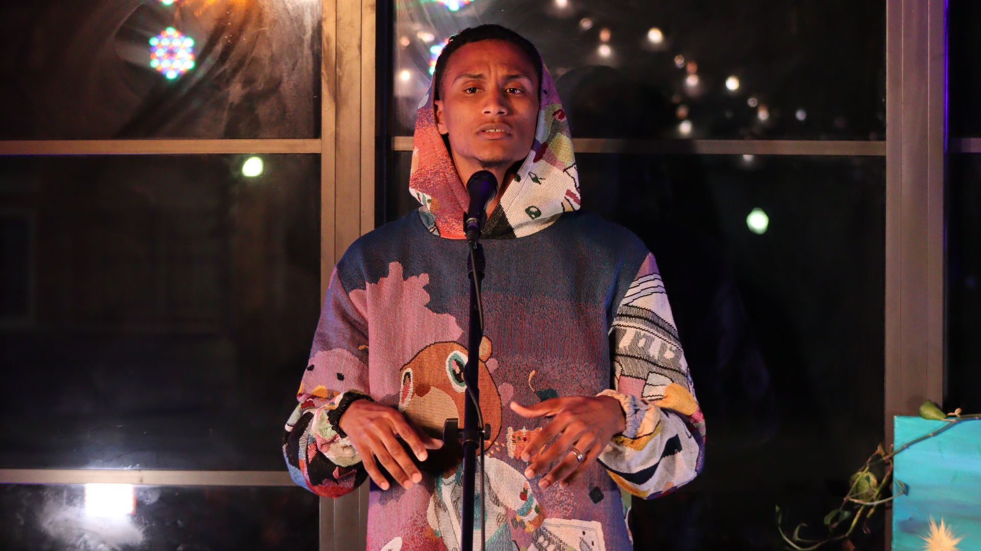 A man in a hoodie is singing into a microphone.