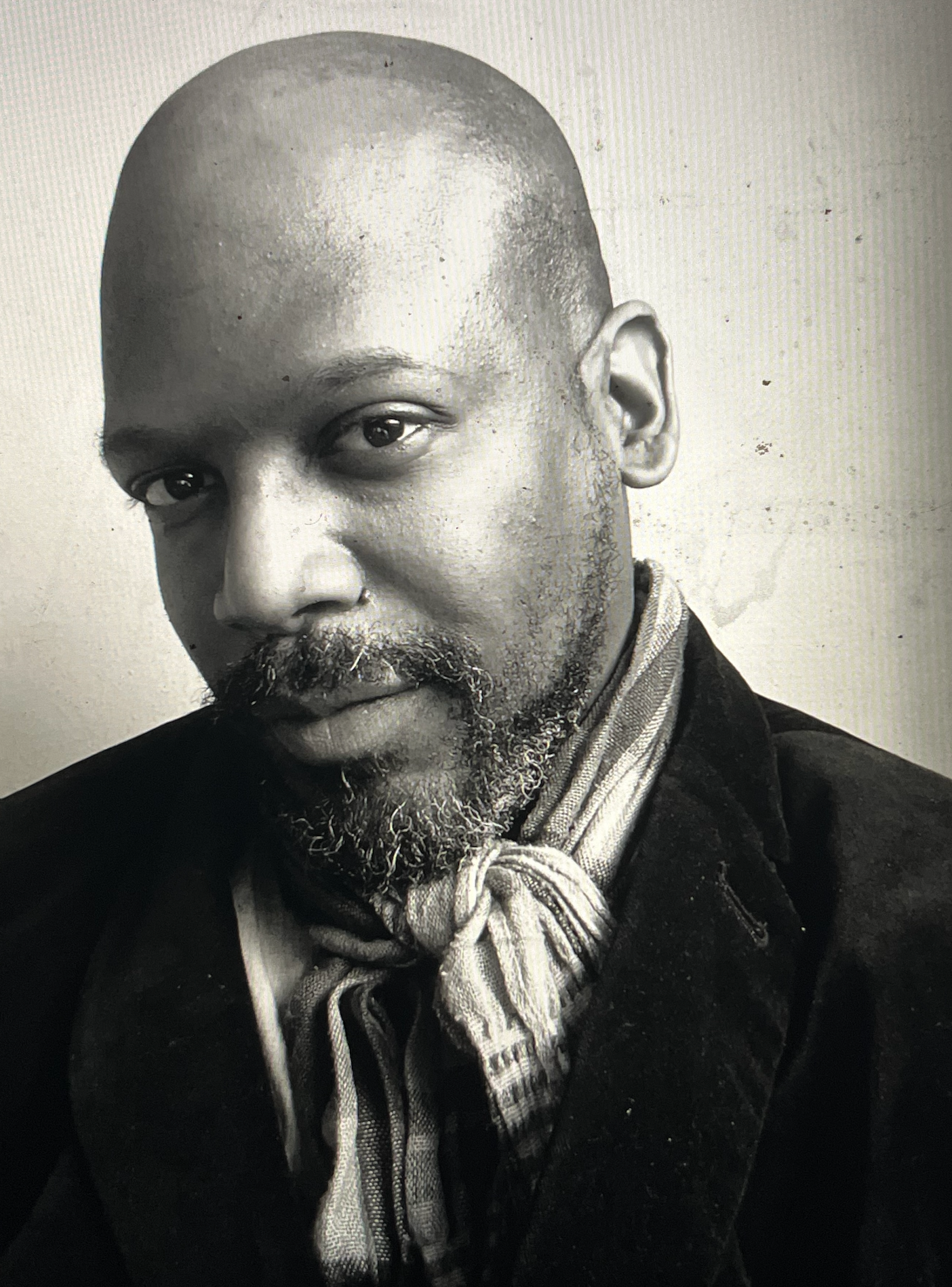 A black and white photo of a bald man with a beard
