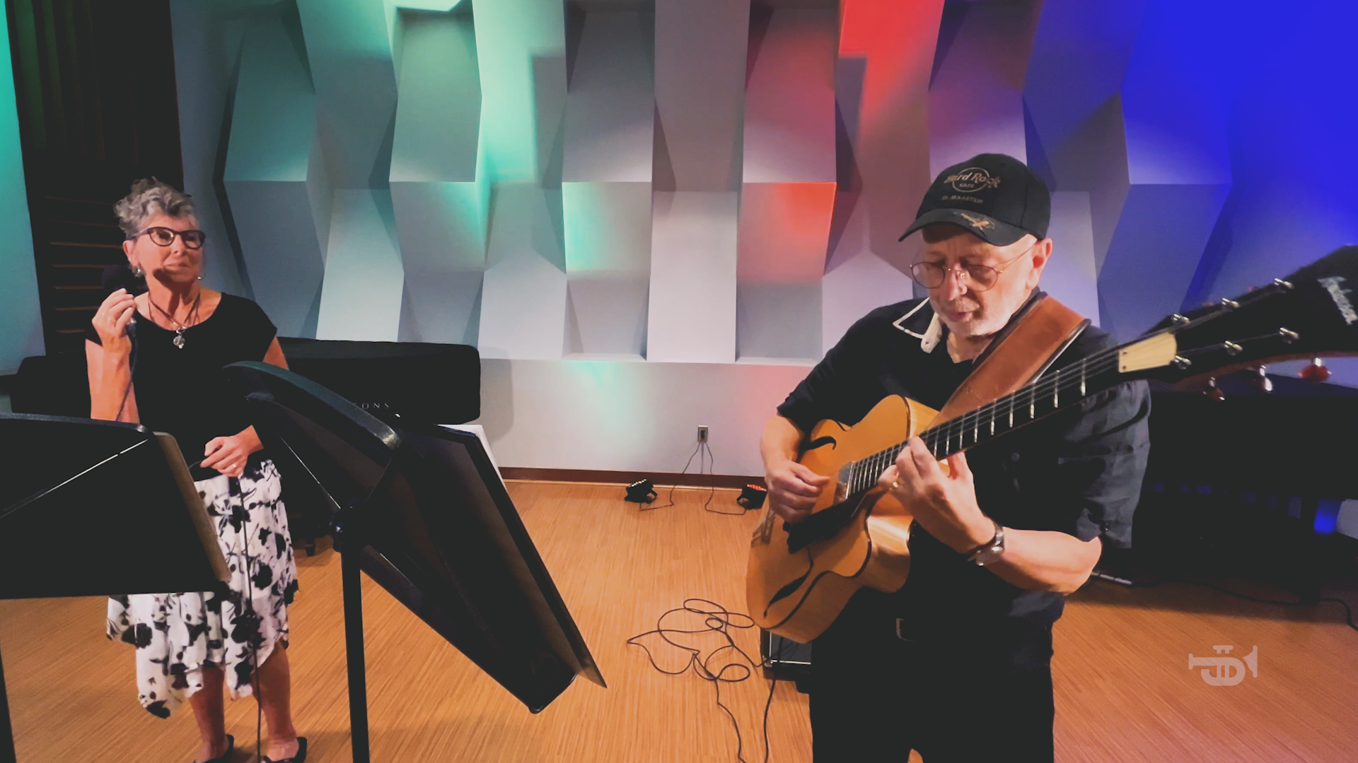 A man is playing a guitar while a woman sings into a microphone.