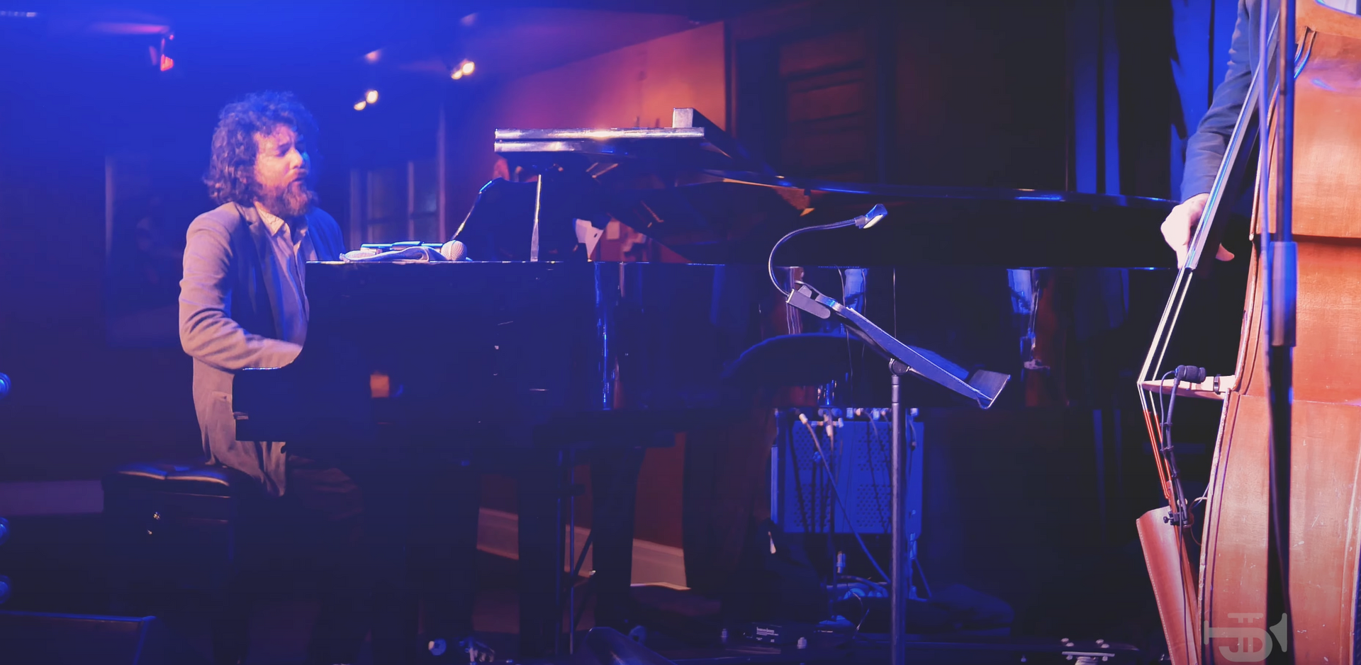 A man is playing a piano on a stage in a dark room.