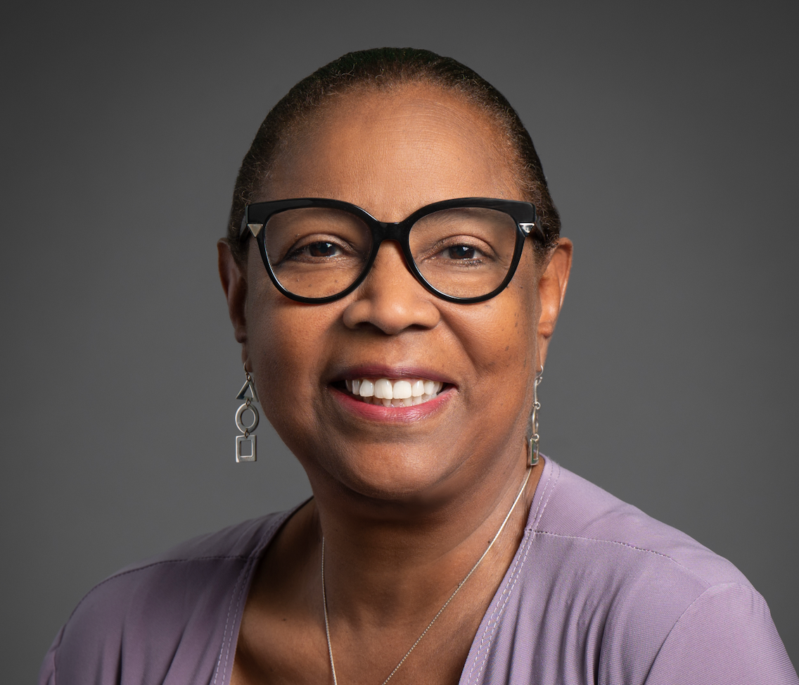 A woman wearing glasses is sitting in front of a microphone