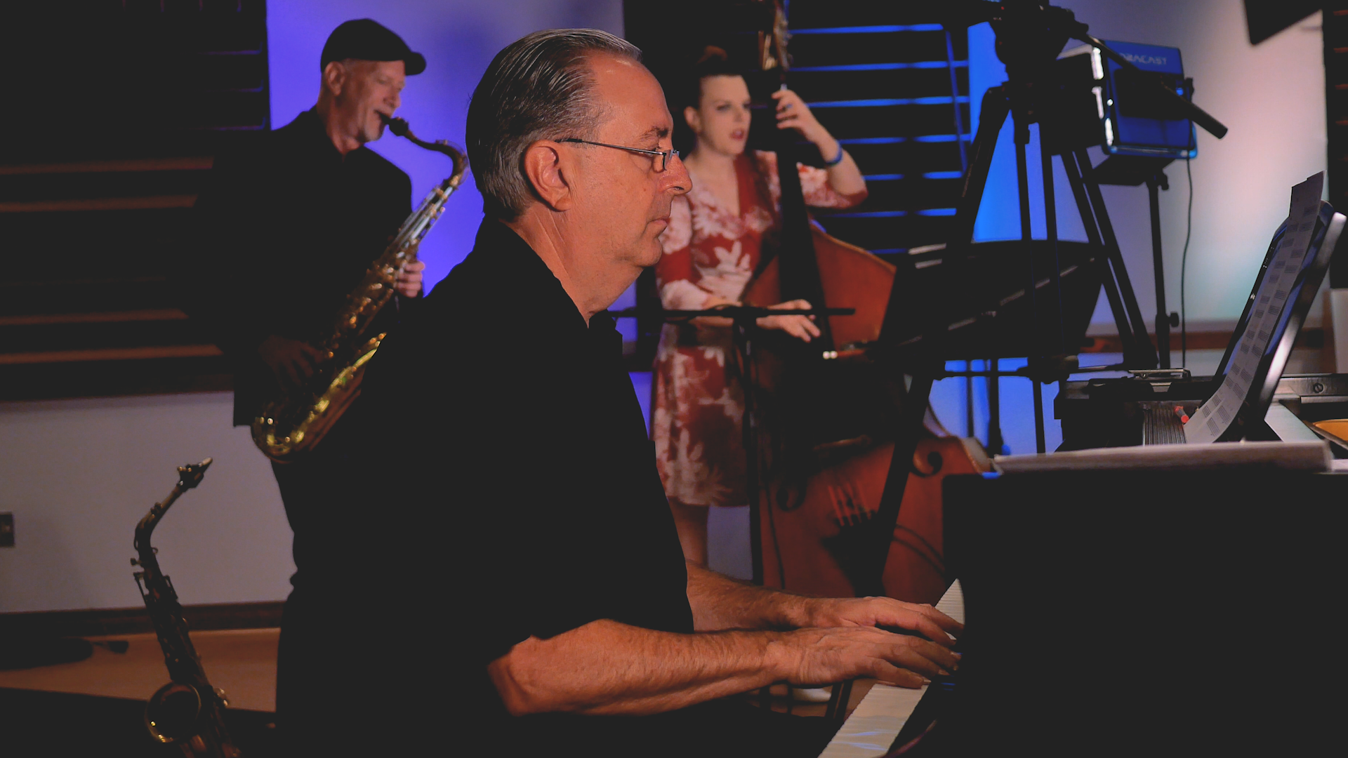 A man is playing a piano in front of a group of musicians.