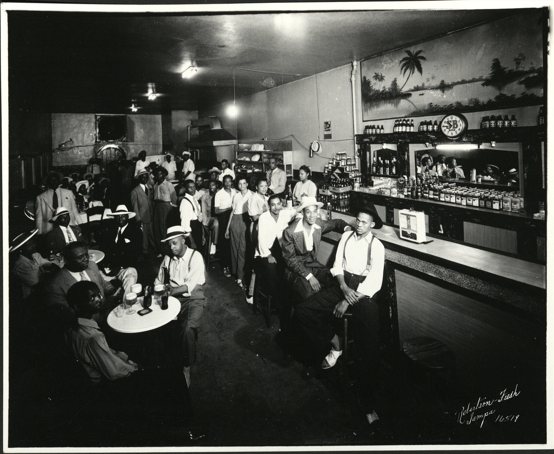 A black and white photo of people sitting at tables in a restaurant