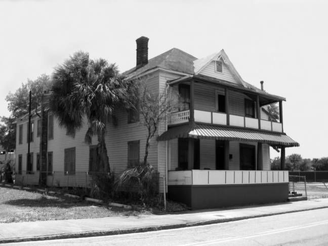 A black and white photo of a house on the side of the road