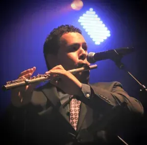 a man in a suit is playing a flute in front of a microphone