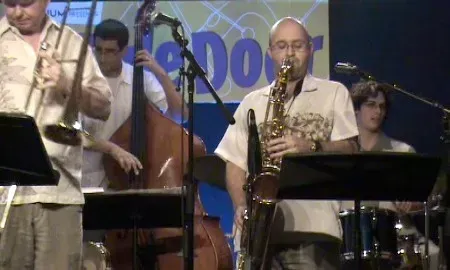 a man is playing a saxophone in a jazz band on stage .