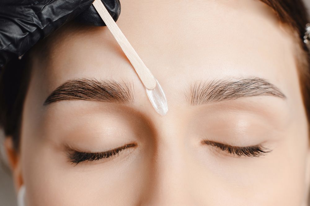 Person Getting Eyebrow Waxed, With Wax Being Applied Between Eyebrows — Bombshell Body Bar In Meikleville Hill, QLD