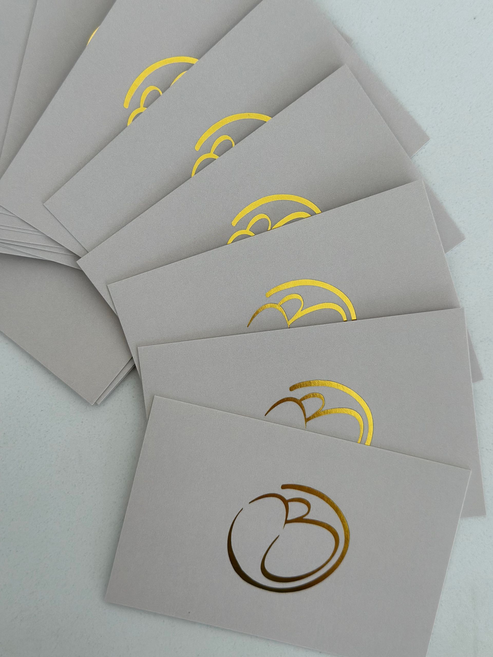 Stack of Gray Envelopes With a Gold Logo on Each — Bombshell Body Bar In Meikleville Hill, QLD