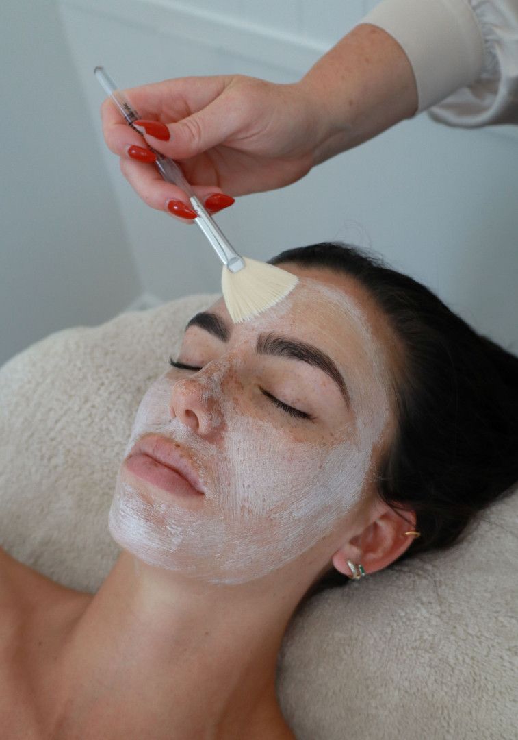 Woman receiving facial mask at a spa; light skin, eyes closed, hand applying mask with a brush.— Bombshell Body Bar In Meikleville Hill, QLD