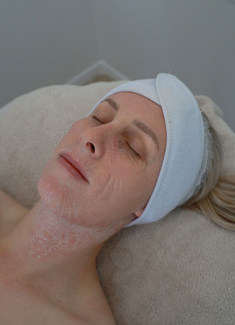 Woman with head wrap, eyes closed, laying on a spa bed; skin treatment on neck and face.— Bombshell Body Bar In Meikleville Hill, QLD