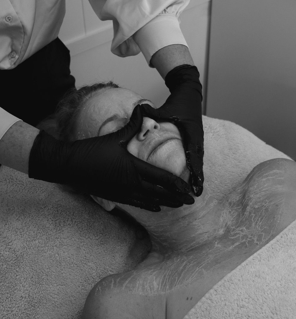 Person receiving facial treatment, hands in black gloves.— Bombshell Body Bar In Meikleville Hill, QLD