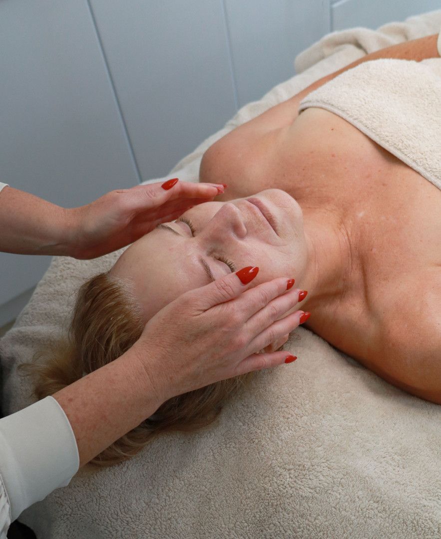 Woman receiving a facial massage, eyes closed, hands gently touching face, in a spa setting.— Bombshell Body Bar In Meikleville Hill, QLD