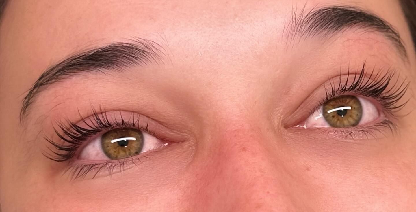 Close-up of a person's eyes and eyebrows. Brown eyes with mascara and thick, dark eyebrows. Skin is light.