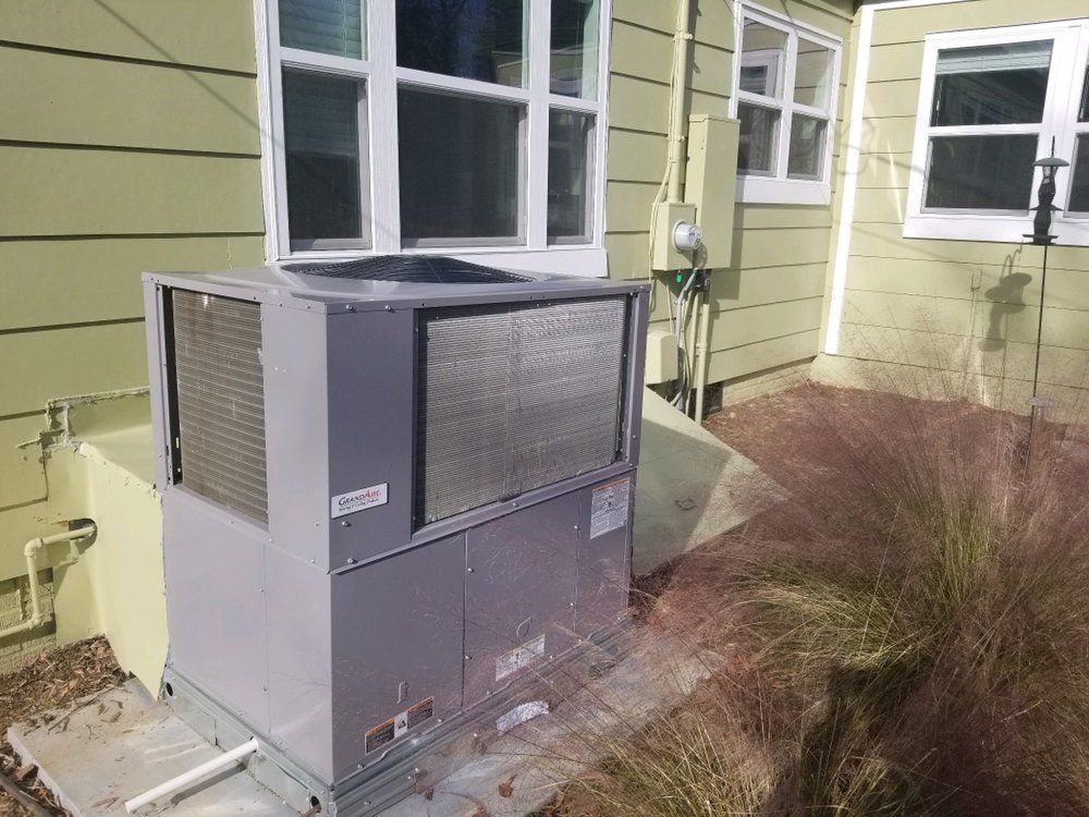 A large air conditioner is sitting in the backyard of a house.
