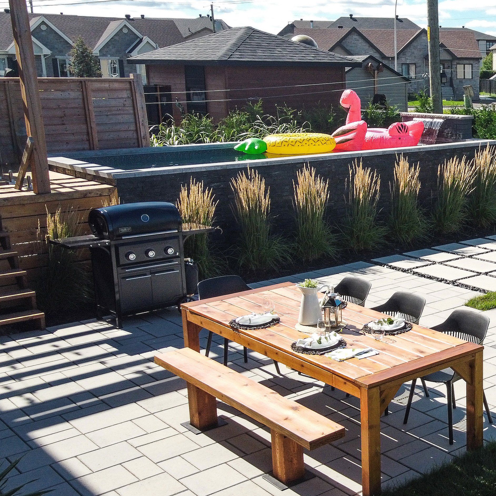 Un patio avec une table et des chaises et une piscine en arrière-plan