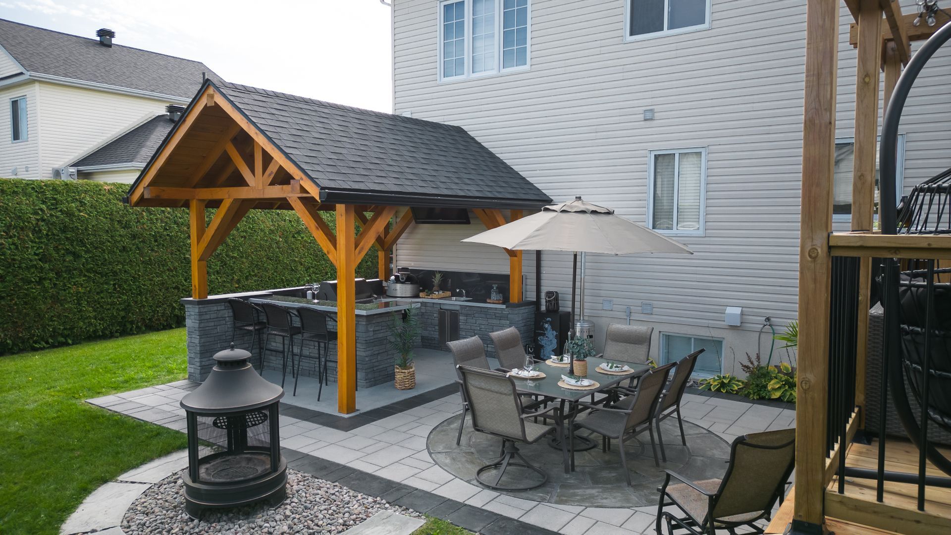 Un patio avec une table, des chaises et un parasol devant une maison.