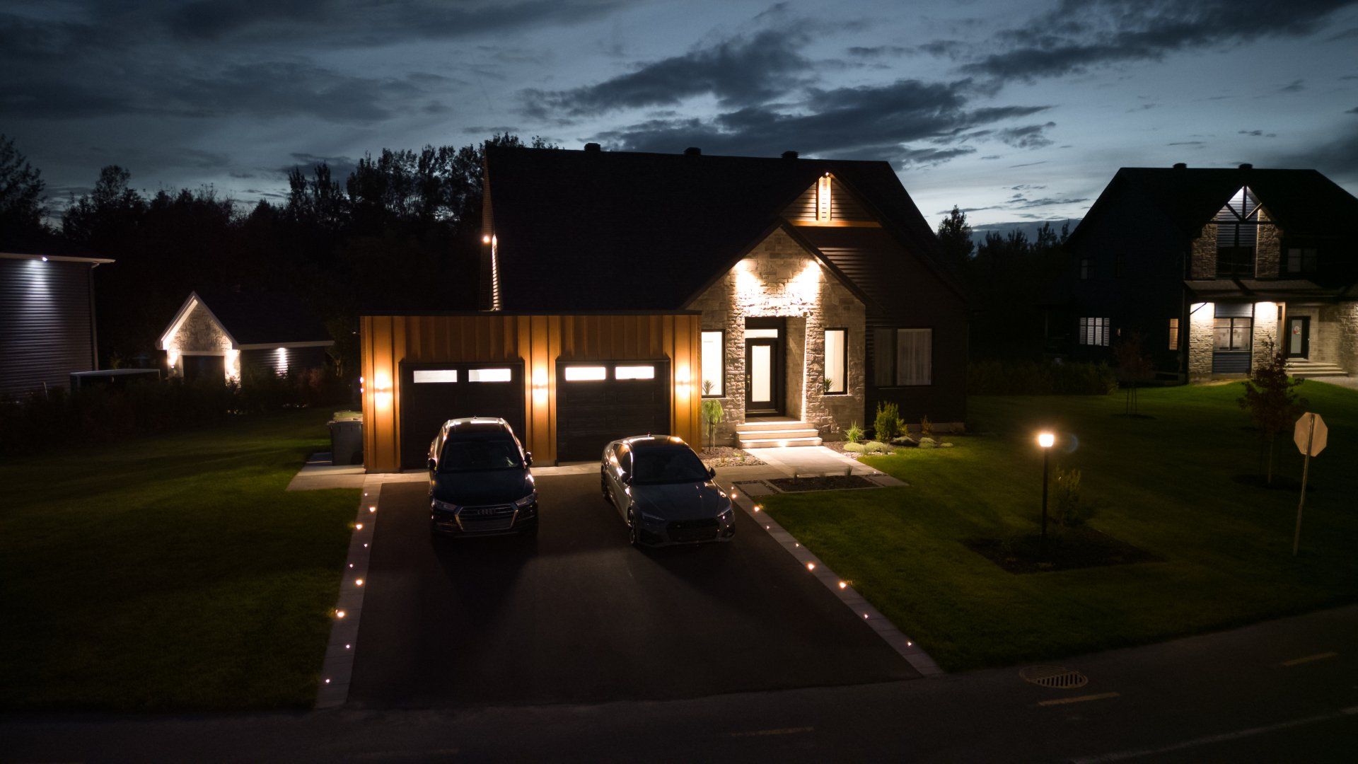 Deux voitures sont garées devant une maison la nuit.