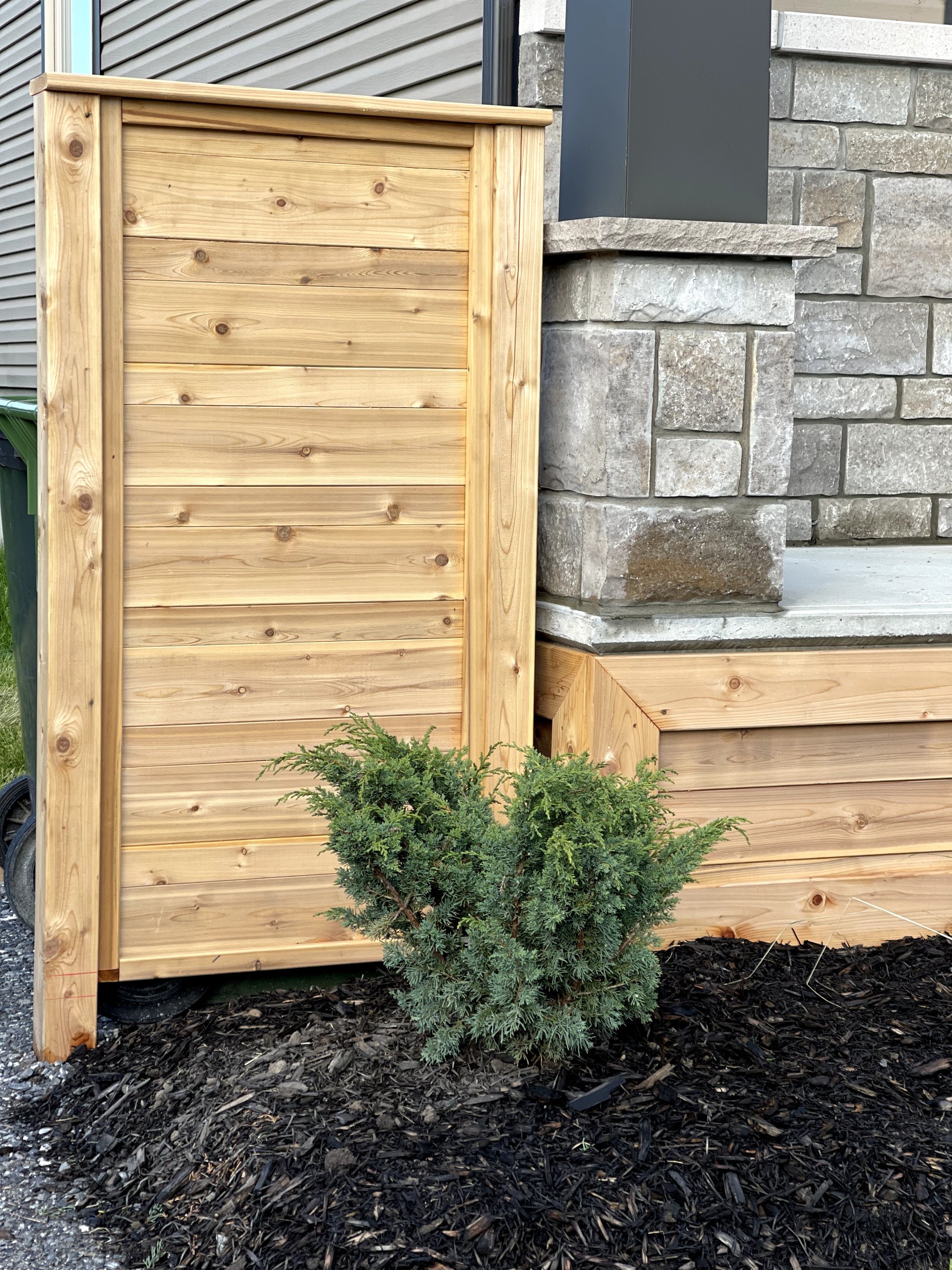 Une clôture en bois est assise à côté d'un mur de briques.