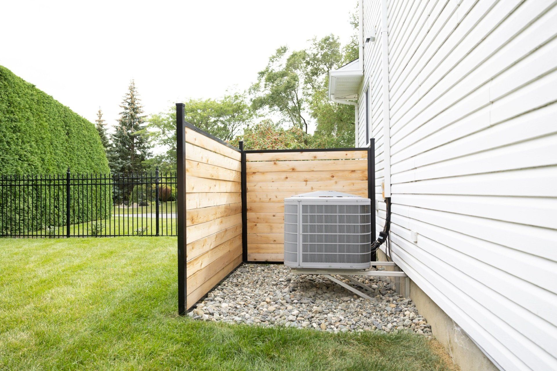 Une maison blanche avec une clôture en bois et un climatiseur dans l'arrière-cour.