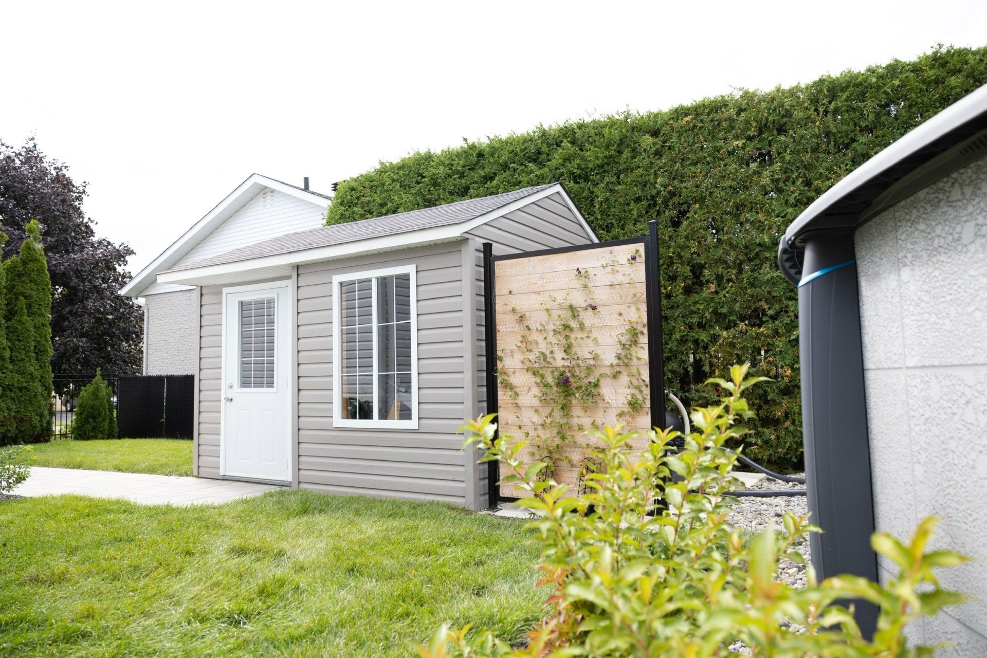 Une petite maison est située au milieu d'une cour verdoyante à côté d'une piscine.