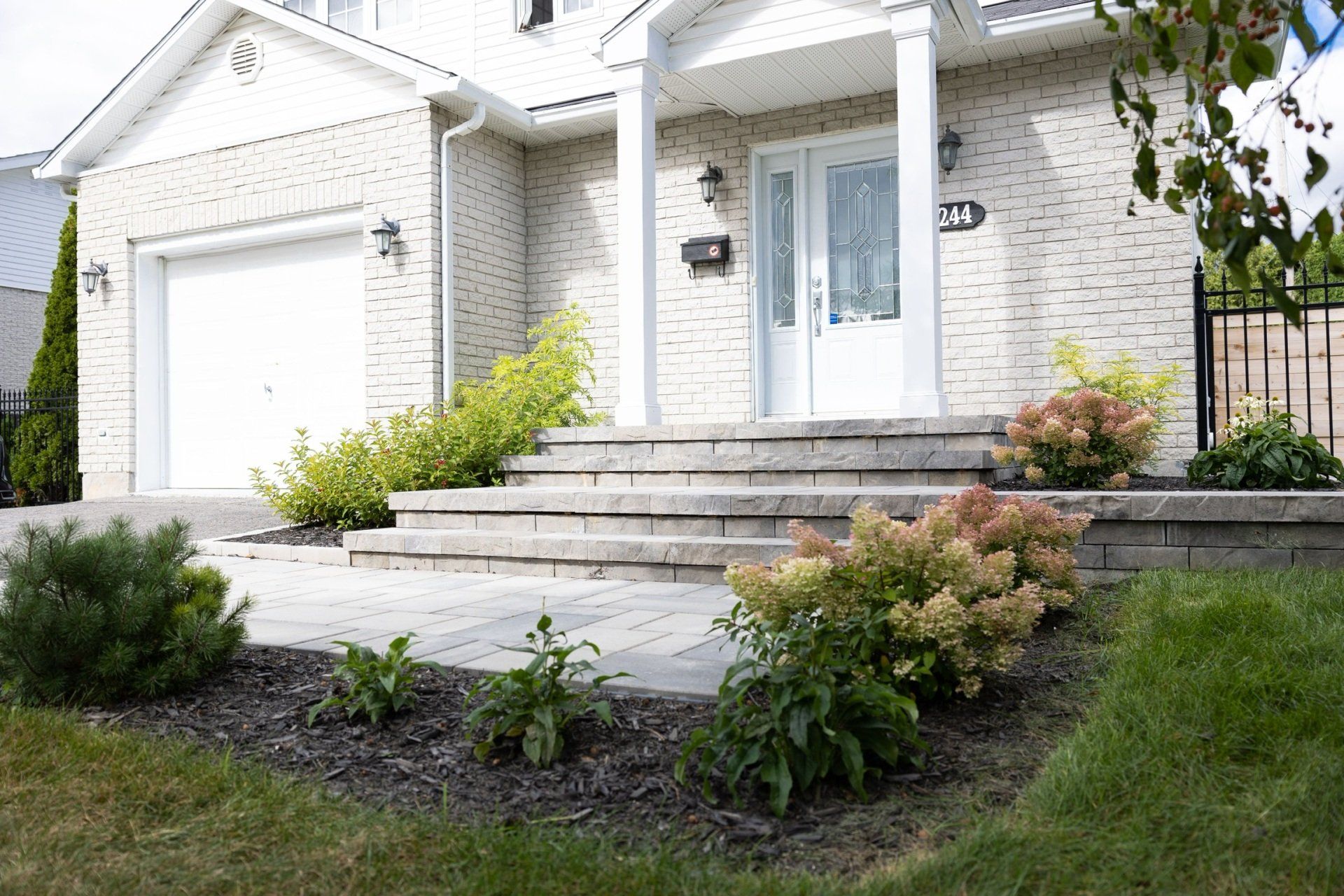 Une maison avec des marches menant à la porte d'entrée, un aménagement paysager et un garage.