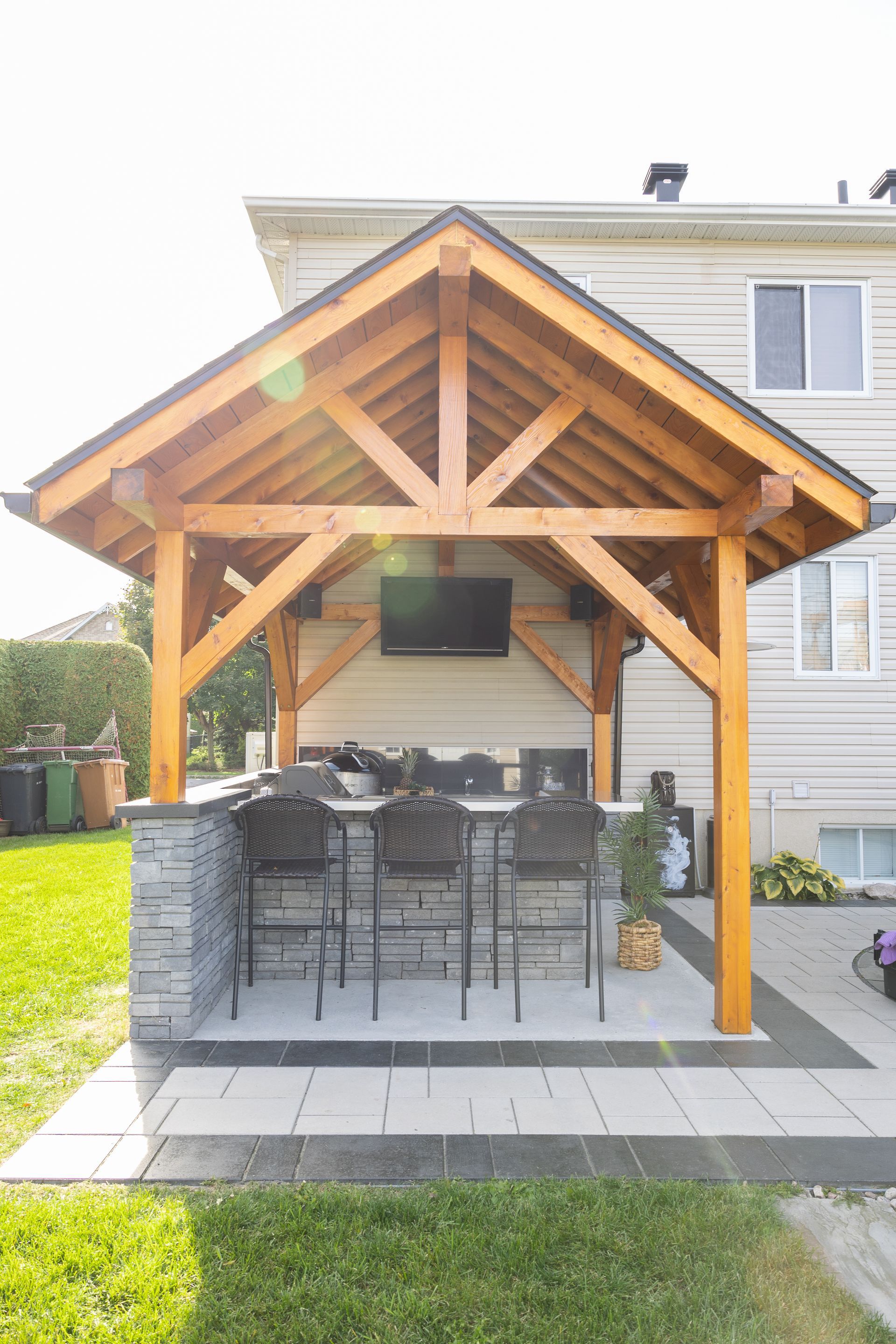 Un gazebo en bois avec une cuisine dans l'arrière-cour d'une maison.