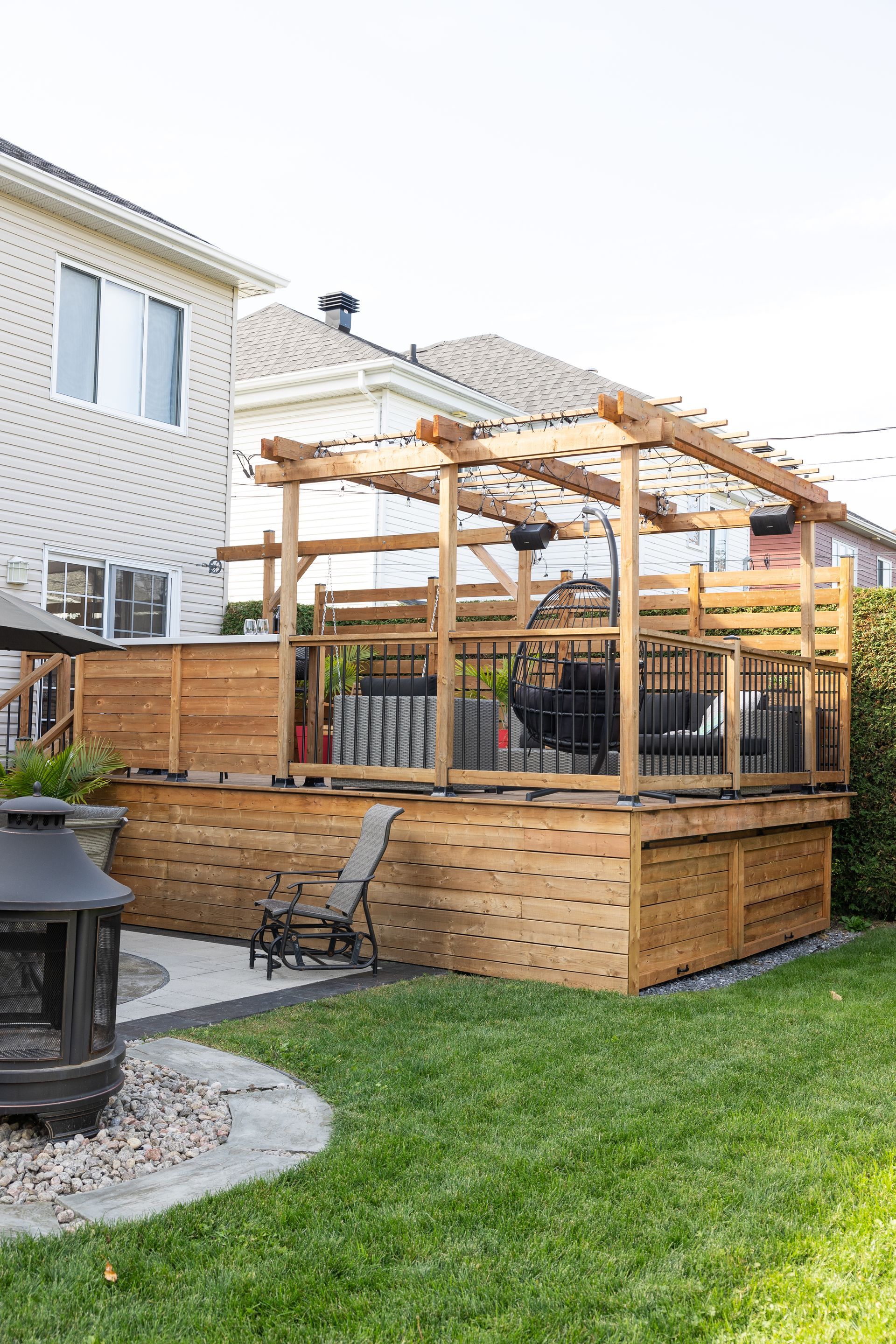 Une terrasse en bois avec une pergola dans l'arrière-cour d'une maison.