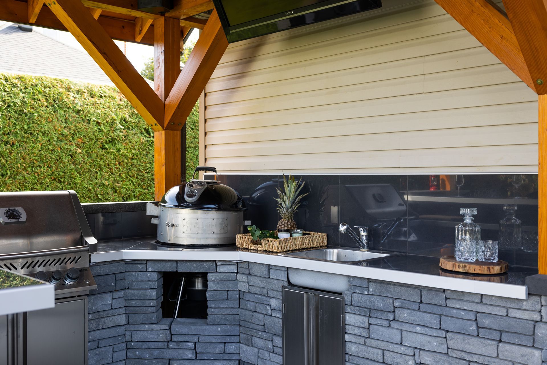 Une cuisine extérieure avec un grill et une télévision au mur