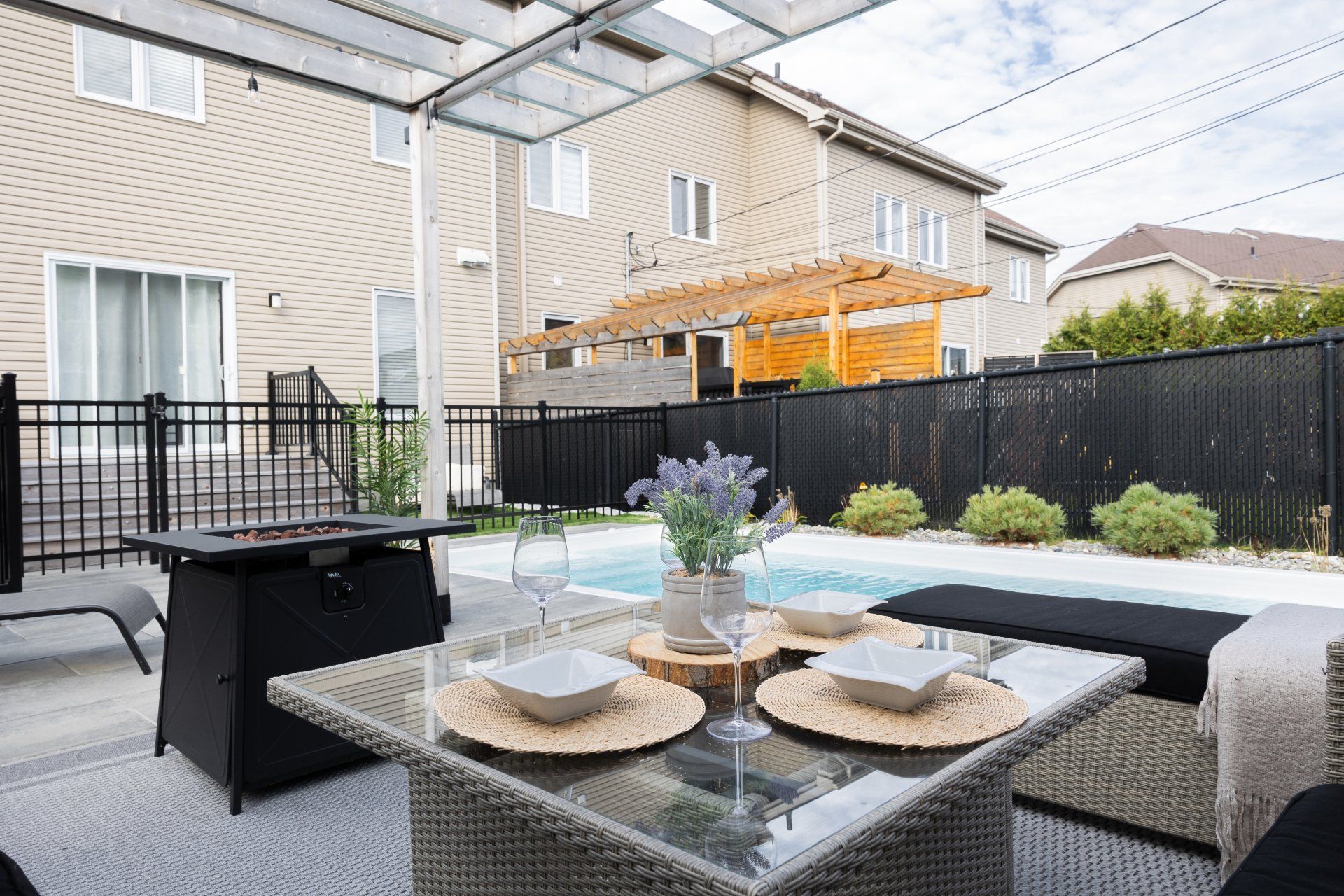 Terrasse avec table à manger, petite piscine et maisons à deux étages en arrière-plan.