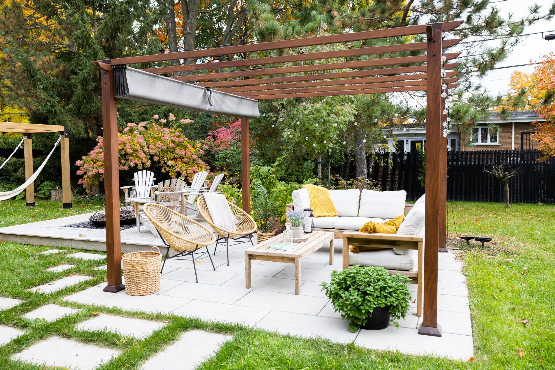 Il y a une pergola dans l'arrière-cour avec un canapé et des chaises en dessous.