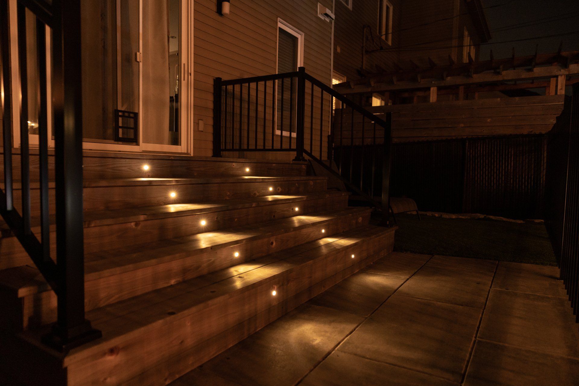 Les escaliers sont éclairés la nuit et il y a une terrasse en arrière-plan.