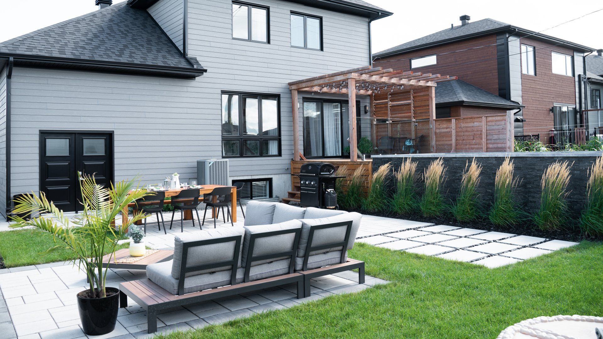 Une cour arrière avec un canapé, une table et des chaises devant une maison.