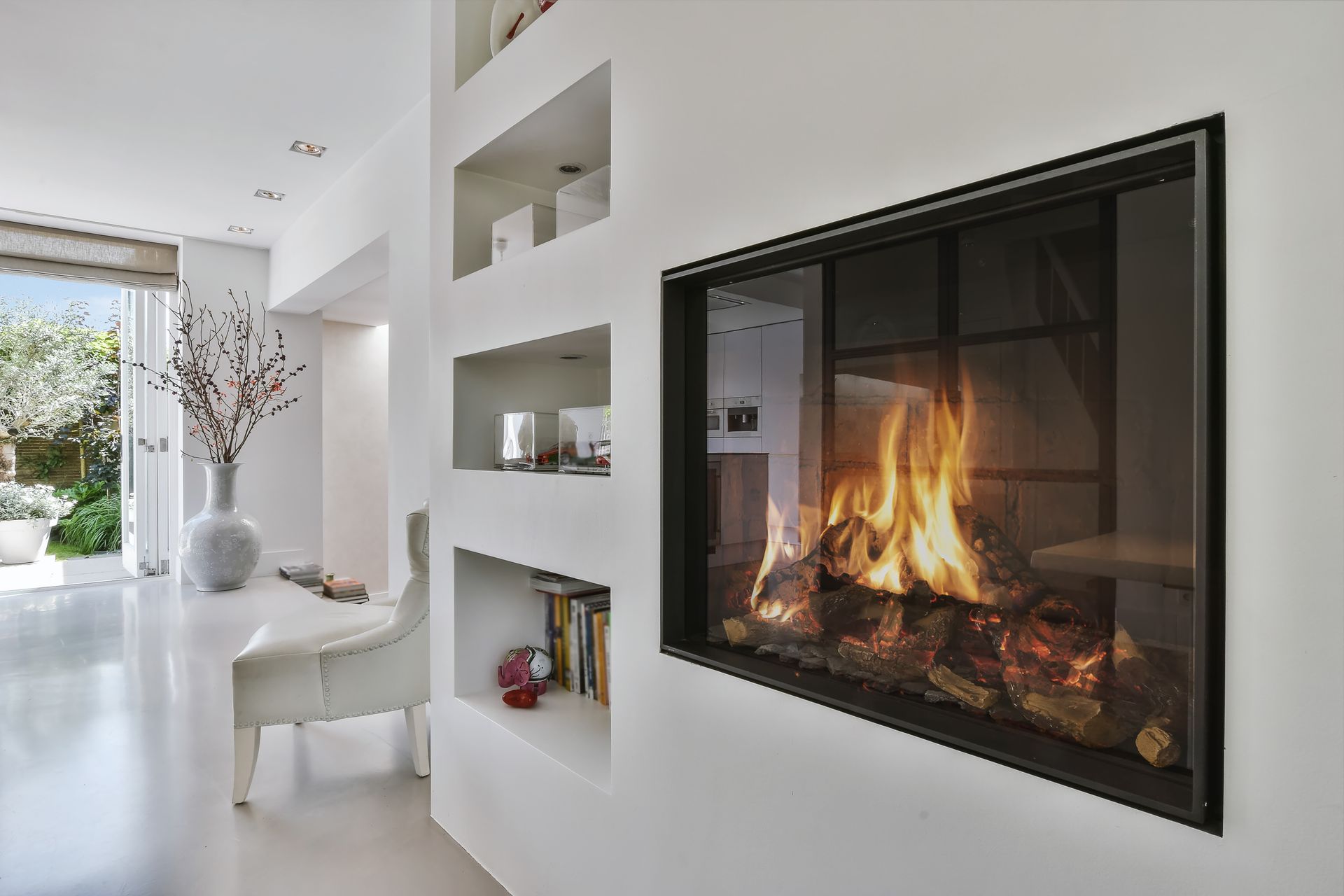Chambre blanche moderne avec cheminée et étagères intégrées, flammes visibles.