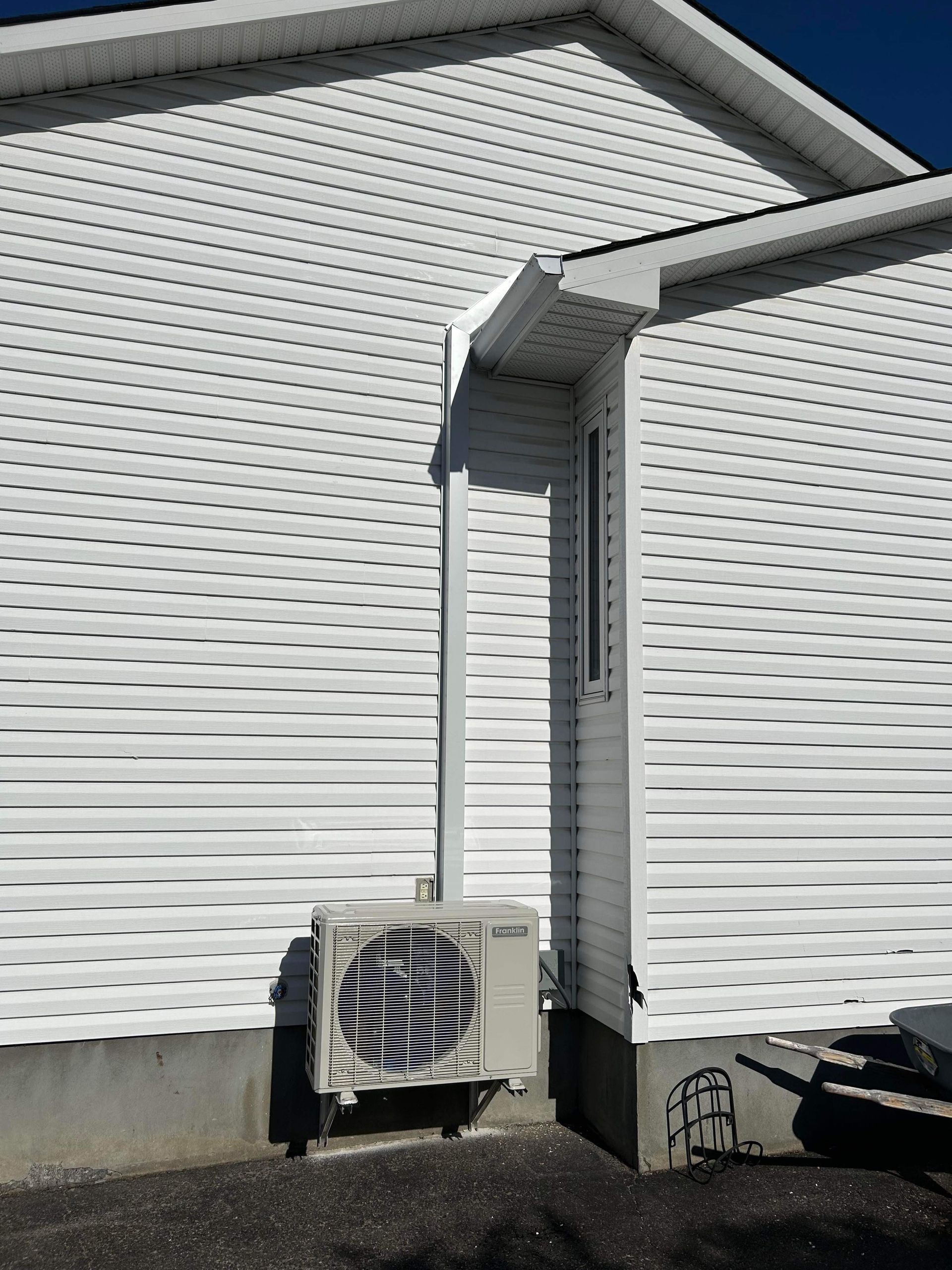 Une maison blanche avec un petit climatiseur sur le côté.