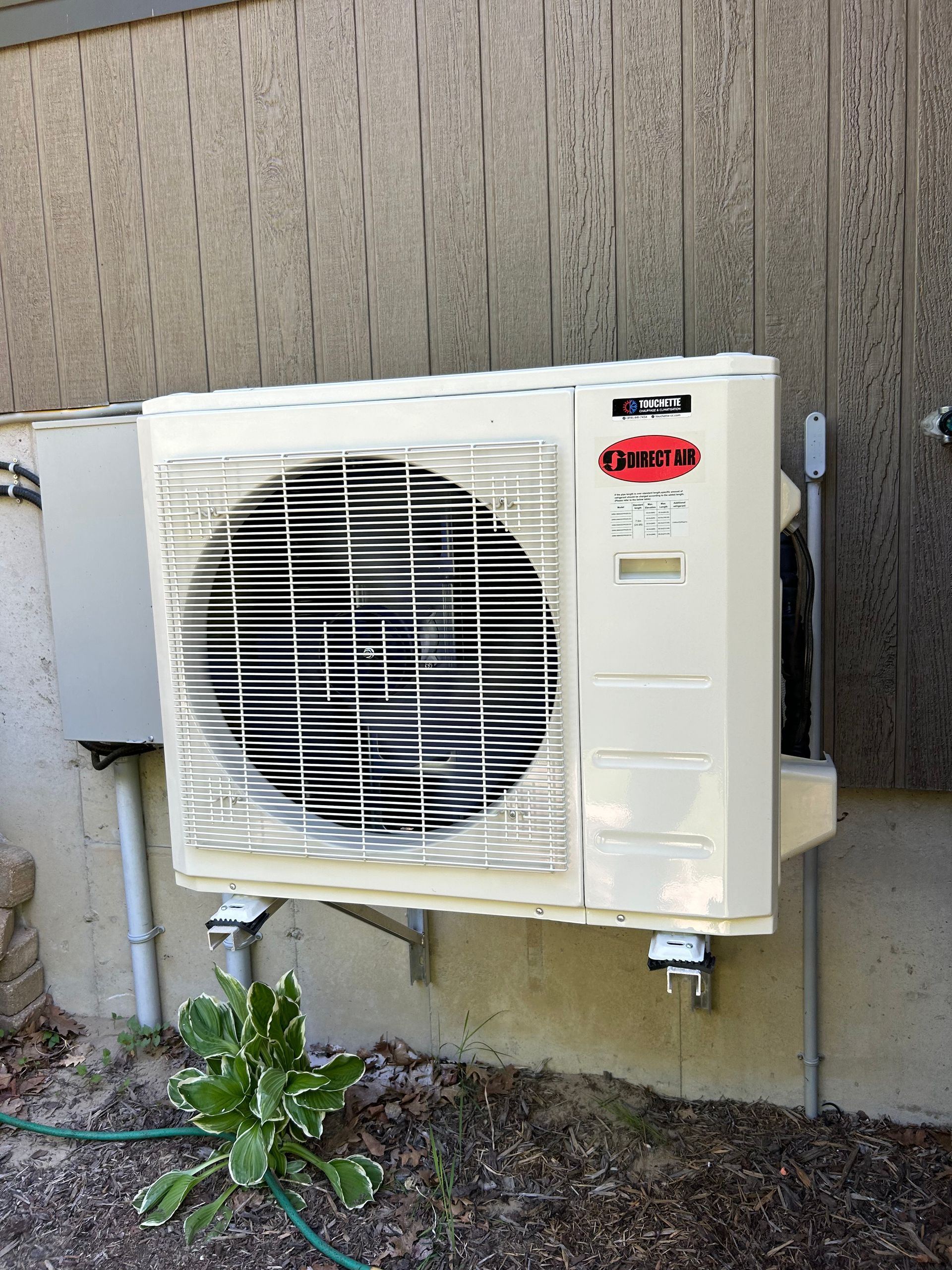 Un climatiseur blanc est monté sur le côté d’un bâtiment.
