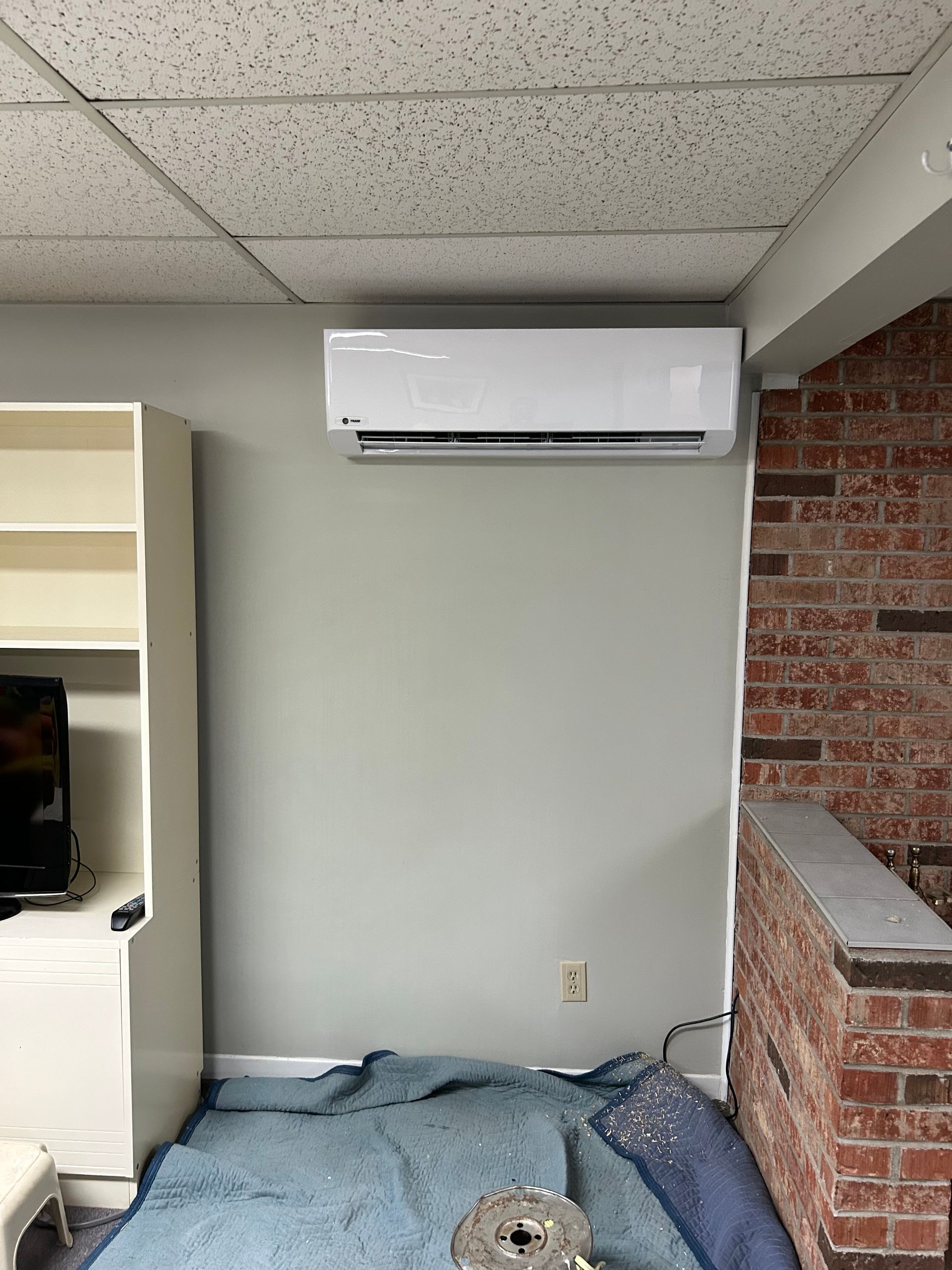 Une pièce avec un climatiseur mural et un mur de briques.