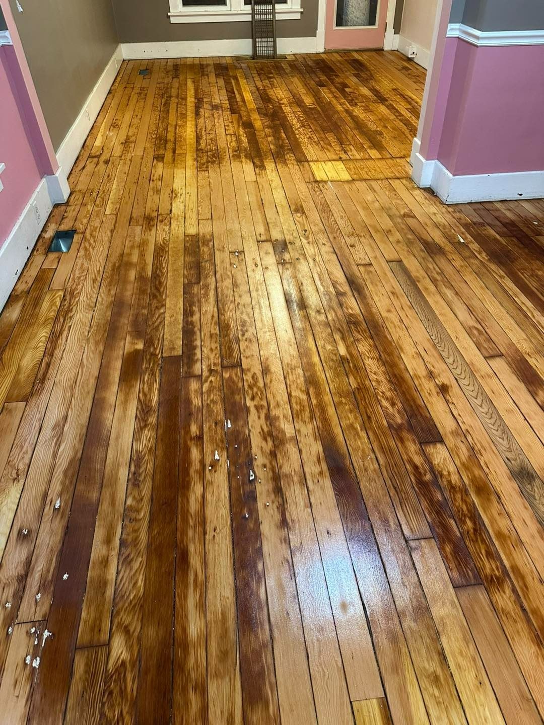 Wooden floor with dark stained patches and debris.