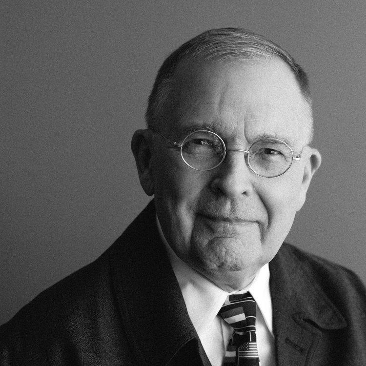 a man wearing glasses and a tie looks at the camera