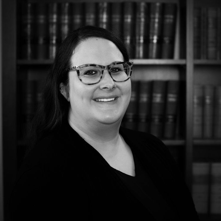 a woman wearing glasses is smiling in front of a bookshelf