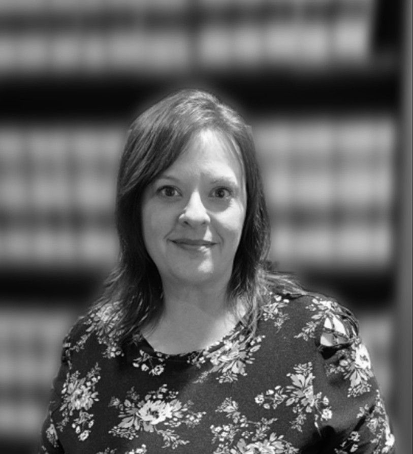 a woman smiling, wearing a dark shirt with white flowers