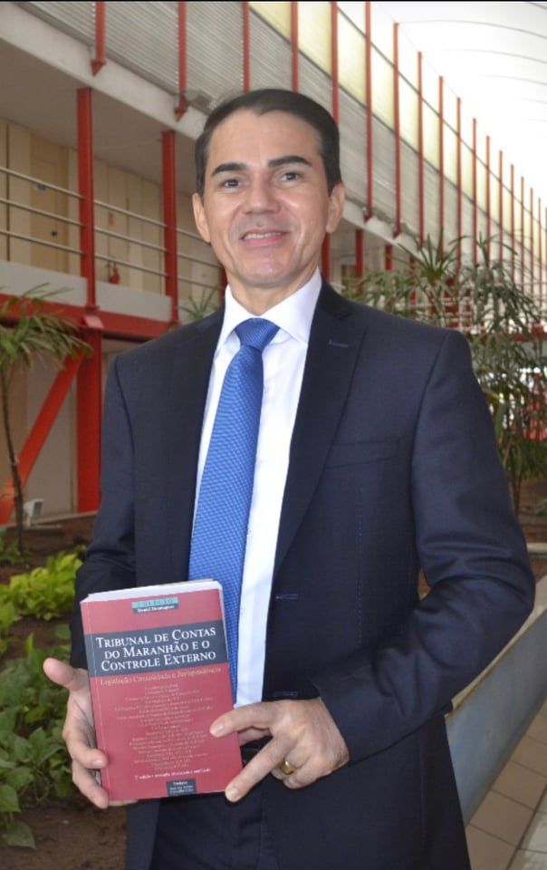 Um homem de terno e gravata está segurando um livro