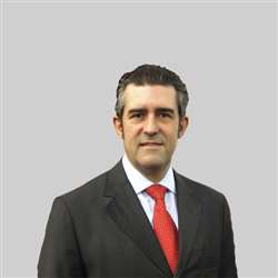 Um homem de terno e gravata está em frente a um fundo cinza.