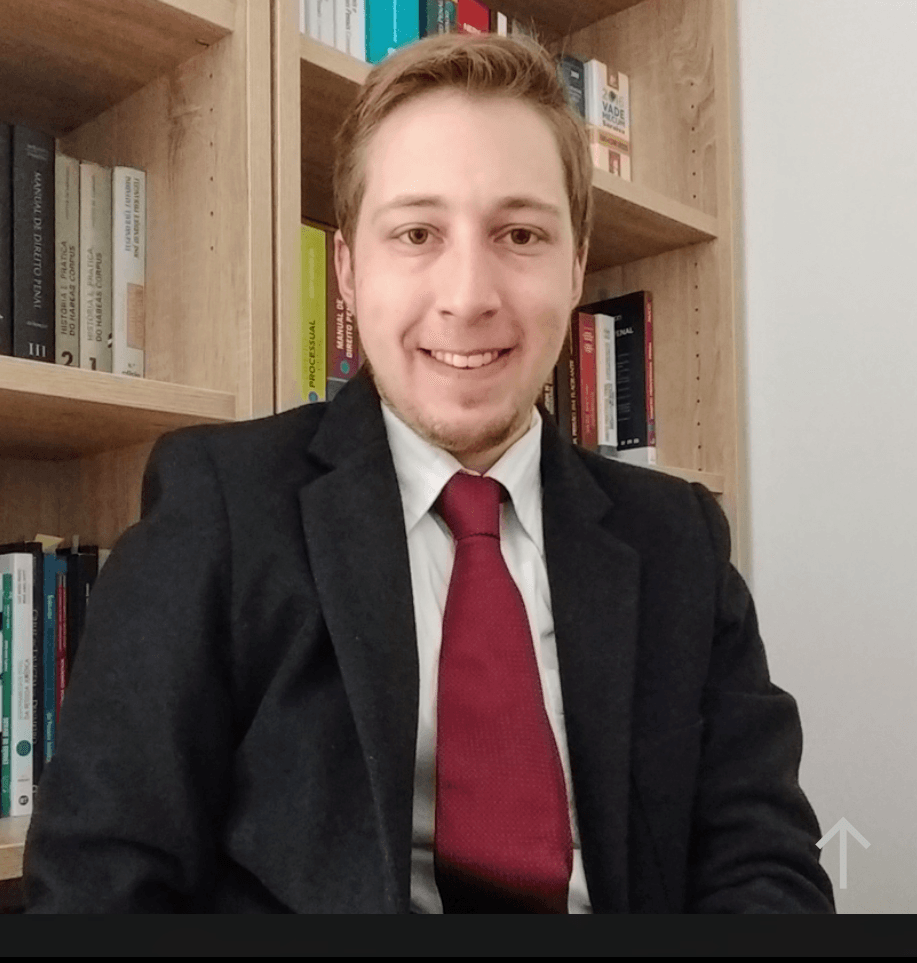 Um homem de terno e gravata está sorrindo na frente de uma estante