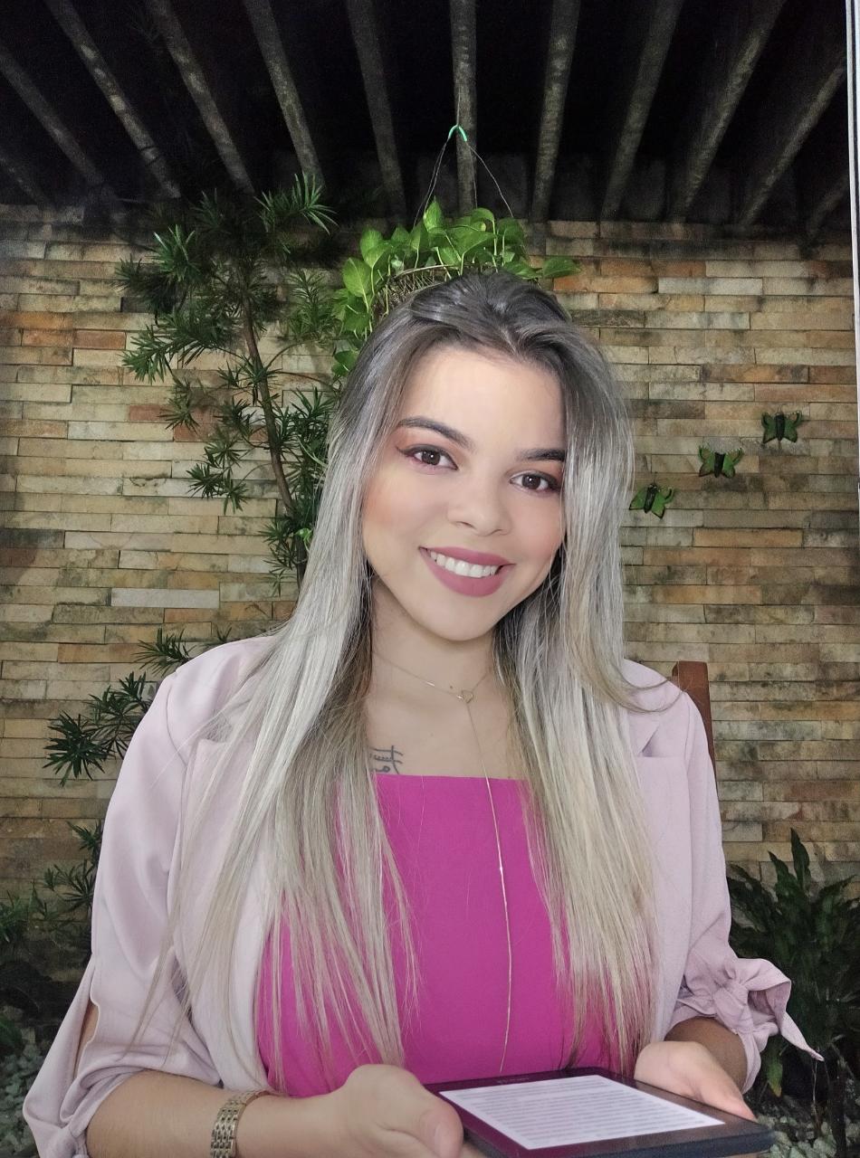 Uma mulher está sentada em frente a uma parede de tijolos segurando um livro.